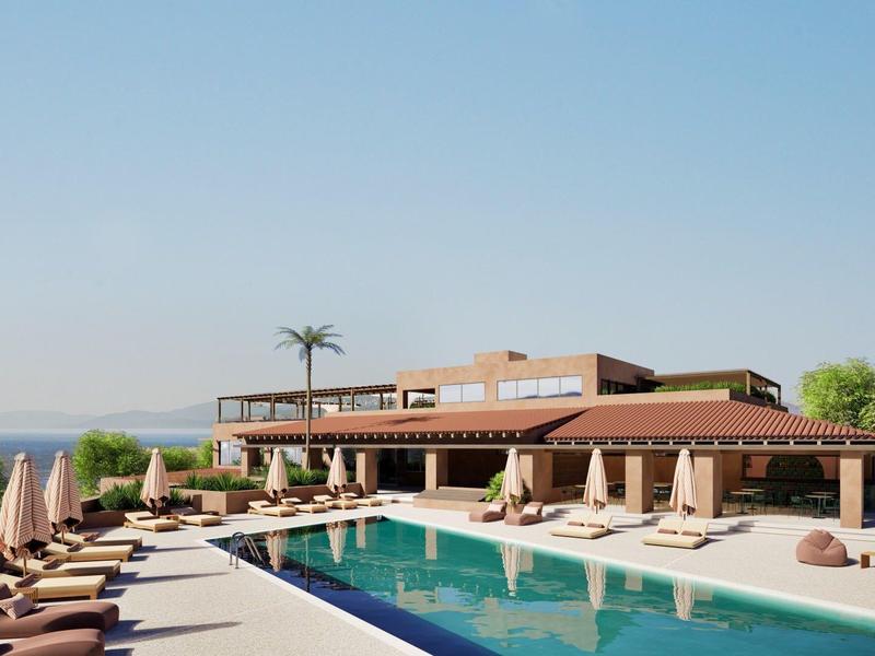 Piscina exterior moderna con tumbonas y vista al mar bajo cielo despejado.
