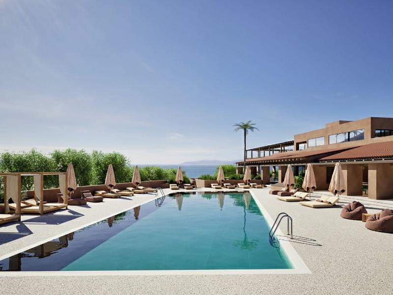 Área de piscina moderna con tumbonas y hotel de varias plantas bajo cielo despejado.