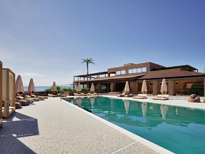 Piscina moderna del hotel con tumbonas y sombrillas bajo un cielo azul despejado.