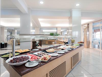 Buffet con vari cibi tra cui olive, salumi e insalate in un'area pranzo luminosa.