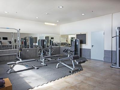 Moderner Fitnessraum mit verschiedenen Trainingsgeräten und hellen Wänden.