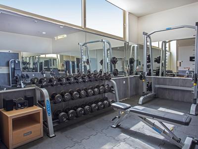 Moderne Fitnessraum mit Hanteln, Gewichtsbank und großem Spiegel.