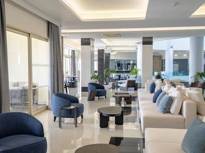 Area lobby di hotel moderna con divani e poltrone in tonalità neutre.