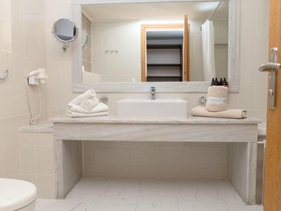 Moderno lavabo da bagno in hotel con specchio e asciugamani bianchi.