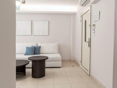 Una stanza ben illuminata con un divano bianco e due tavoli rotondi neri.