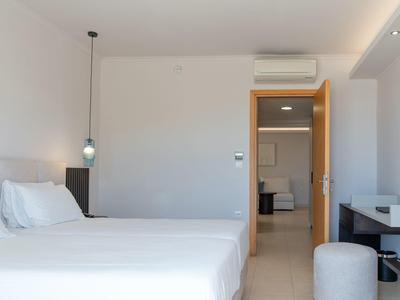 Camera d'hotel moderna con due letti e vista sulla stanza adiacente.