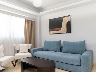 Soggiorno moderno con divano blu, poltrone e arte astratta sulla parete.