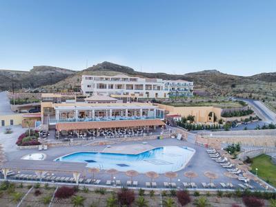 Grande hotel con piscina all'aperto in paesaggio collinare sotto cielo sereno.