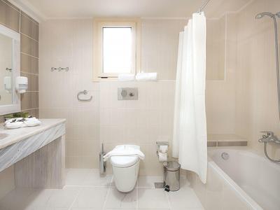 Bagno luminoso con WC, lavabo, specchio e vasca da bagno con tenda per doccia.