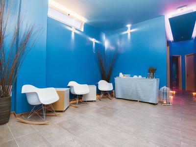 Moderna hall dell'hotel con pareti blu, sedie bianche e tavolo reception decorato.