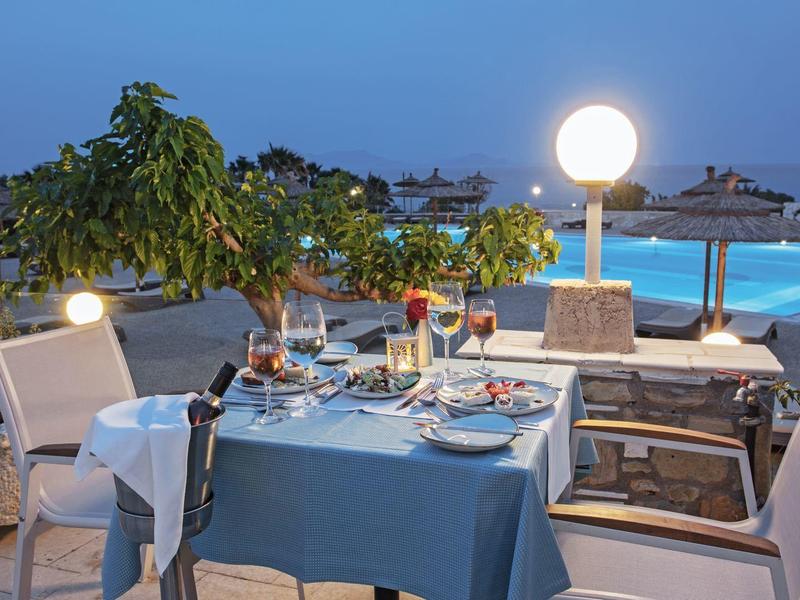 Tavolo da pranzo all'aperto vicino a una piscina con illuminazione serale e sedie comode.