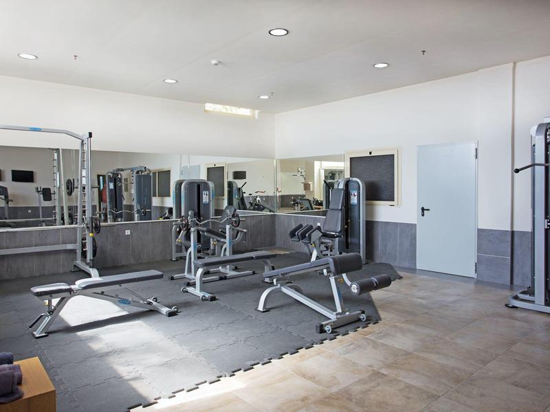 Palestra luminosa dell'hotel con attrezzature moderne e grande specchio a parete.