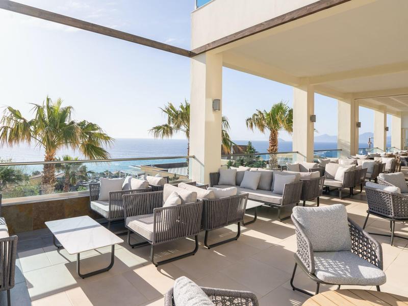 Lounge moderna con aree salotto e vista mare in una giornata di sole.