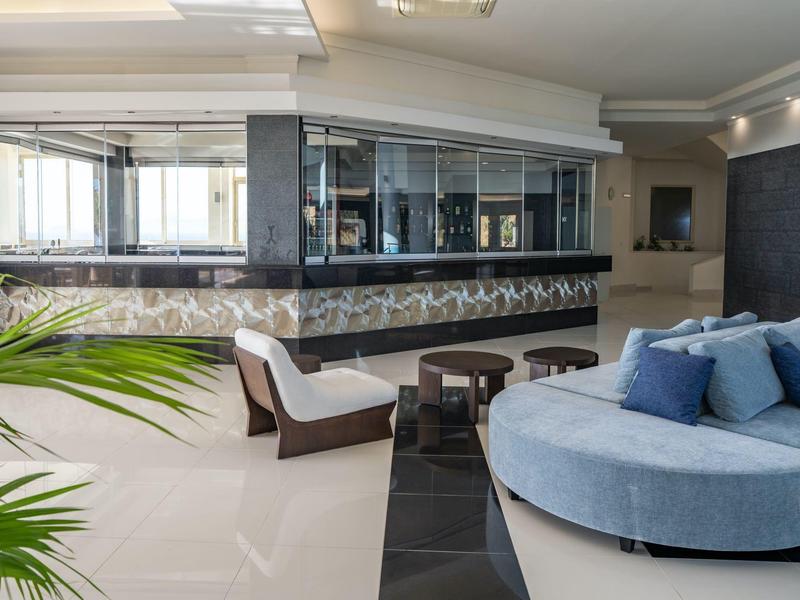 Area lounge elegante dell'hotel con sedute blu e bar moderno sullo sfondo.