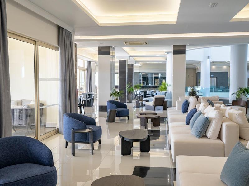 Area lobby di hotel moderna con divani e poltrone in tonalità neutre.