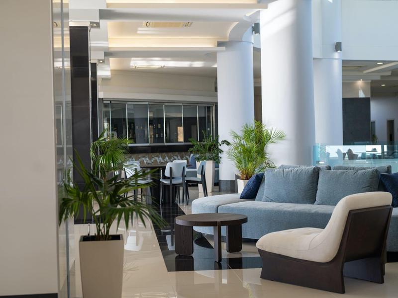 Lobby d'hotel moderna con poltrone, divano e piante in uno spazio luminoso.