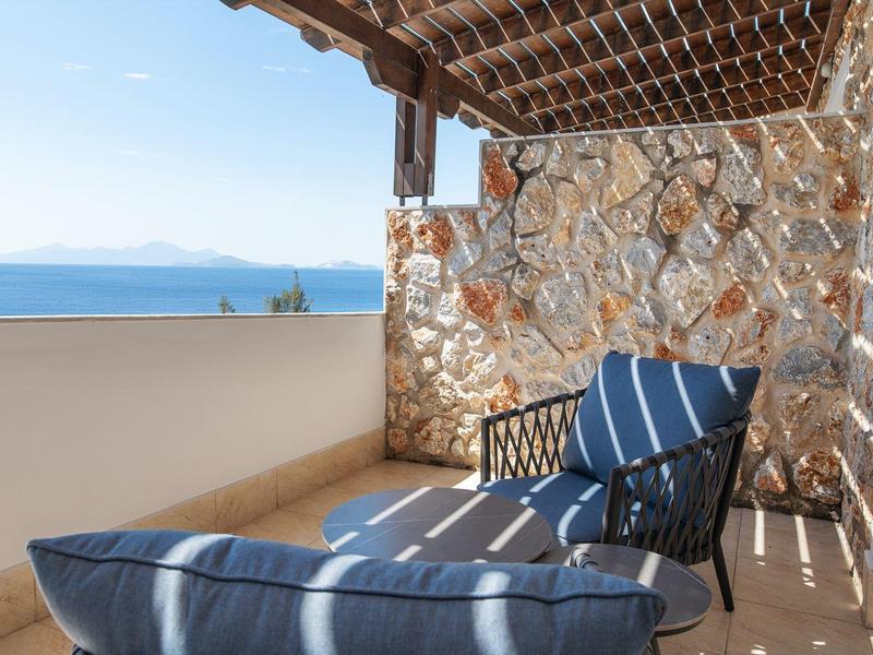 Balcone con sedie in vimini con vista mare in una giornata di sole.