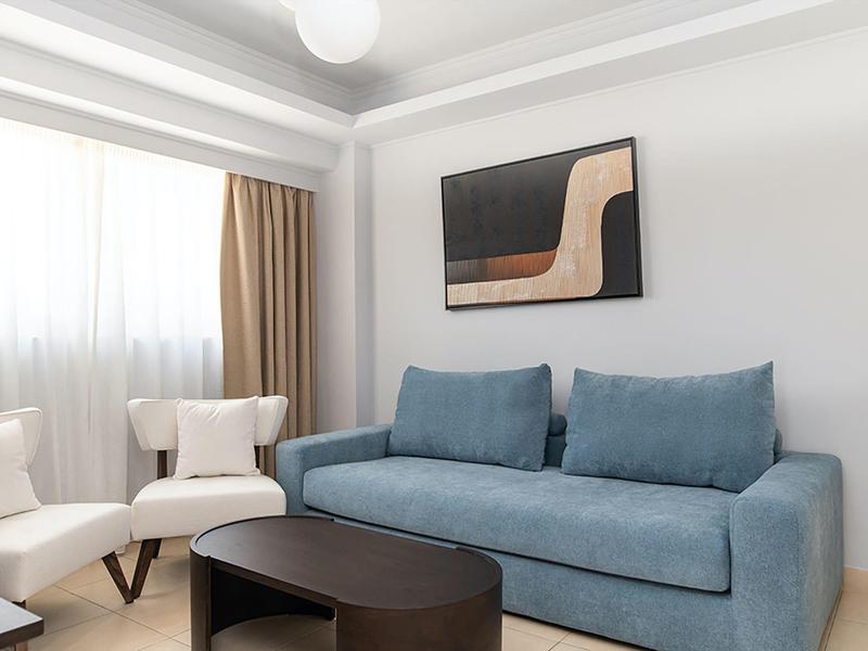 Soggiorno moderno con divano blu, poltrone e arte astratta sulla parete.