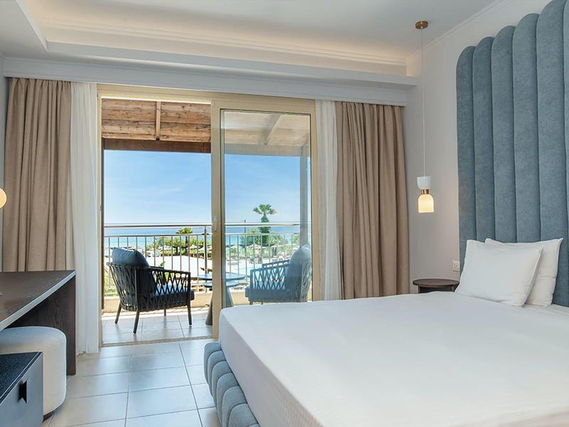 Camera d'hotel moderna con letto, balcone e vista mare.