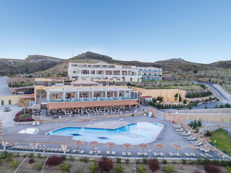 Grande hotel con piscina all'aperto in paesaggio collinare sotto cielo sereno.
