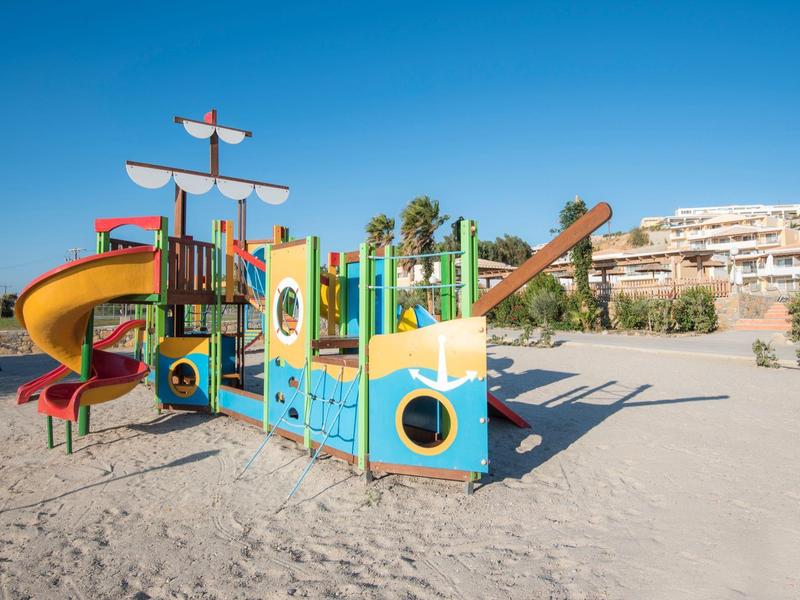Struttura colorata a forma di nave su sabbia sotto un cielo azzurro.