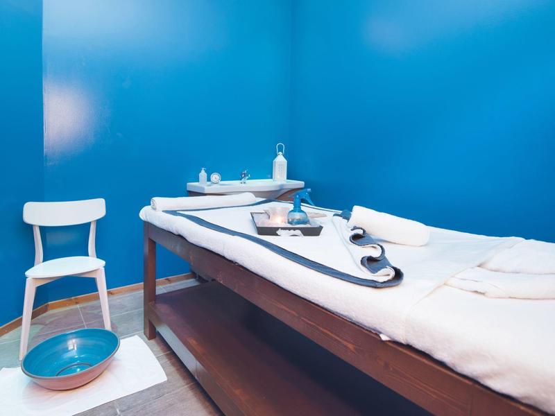 Sala spa rilassante con pareti blu, lettino da massaggio, sedia e accessori spa.