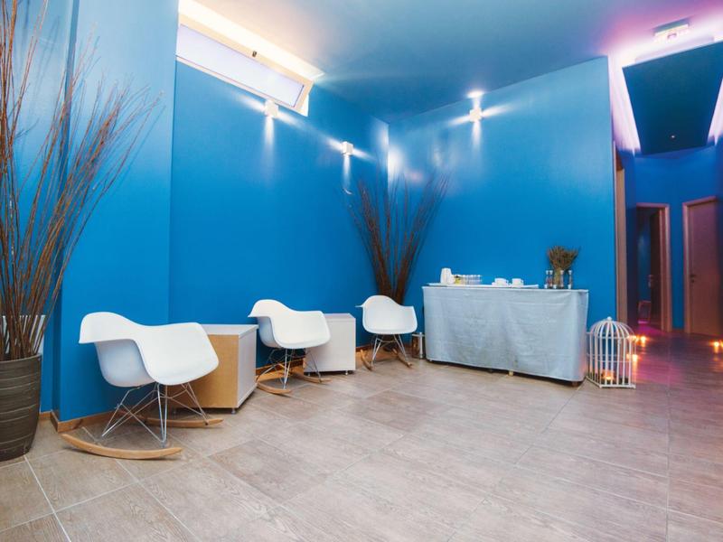 Moderna hall dell'hotel con pareti blu, sedie bianche e tavolo reception decorato.