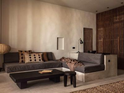 Modernes Wohnzimmer mit grauem Sofa, Holztisch und dekorativen Kissen in warmen Tönen.