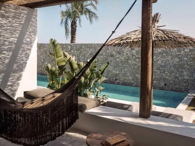 Gemütliche Hängematte auf einer Terrasse mit Pool und tropischen Pflanzen im Hintergrund.