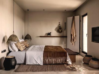 Modernes Schlafzimmer mit braunem Bett und zwei runden Hängelampen an der Wand.