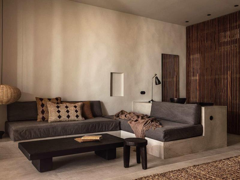 Modernes Wohnzimmer mit grauem Sofa, Holztisch und dekorativen Kissen in warmen Tönen.