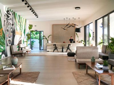 Heller Hotel-Loungebereich mit Pflanzen, Kunstwerken und bequemen Sitzgelegenheiten.