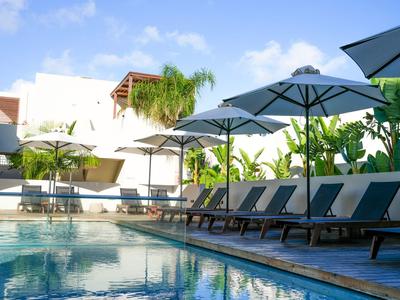 Poolbereich mit Sonnenliegen und Sonnenschirmen in einer Hotelanlage bei Tageslicht.
