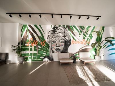 Moderne Hotellobby mit Wandkunst, weißen Sesseln und pflanzlicher Dekoration.