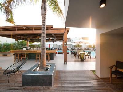 Moderner Außenbereich eines Hotels mit Lounge-Möbeln und Blick auf das Meer bei Sonnenuntergang.