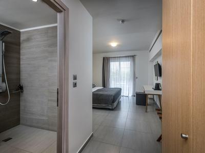 Modernes Hotelzimmer mit Dusche, Bett und Schreibtisch, schlicht und funktional gestaltet.