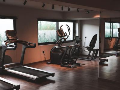 Moderner Fitnessraum mit Laufband, Crosstrainer und Spiegelwänden in einem Hotel.