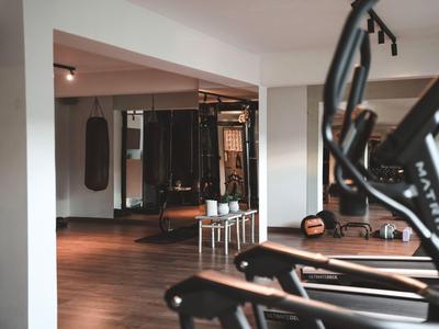 Moderne Hotel-Fitnessstudio mit Hantelbank, Trainingsausrüstung und Holzfußboden.