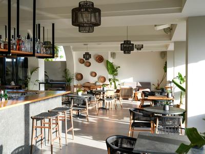 Heller Innenraum einer modernen Hotelbar mit Holzboden, Sitzgelegenheiten und Dekoration an der Wand.