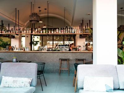 Moderner Hotelbarbereich mit weißen Möbeln und dekorativem Lichtdesign.