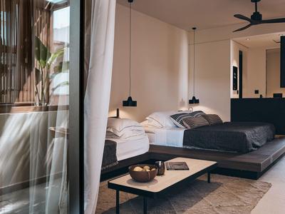 Modernes Hotelzimmer mit zwei Betten, schlichter Einrichtung und großen Fenstern mit Blick ins Grüne.