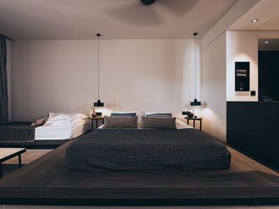Modernes Schlafzimmer mit großem Doppelbett, Sesseln und schwarzen Akzenten in einem Hotelzimmer.