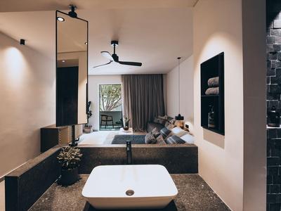 Modernes Hotelzimmer mit freistehender Badewanne, Sofa und Blick auf einen Balkon.
