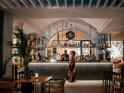 Frau steht in stilvoller Hotelbar mit gedämpfter Beleuchtung und moderner Einrichtung.