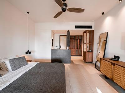 Modernes Hotelzimmer mit Doppelbett, Deckenventilator, Hängelampen und Holzverkleidung.