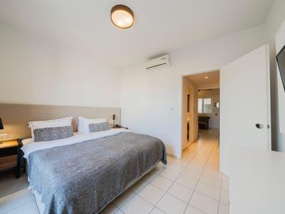 Hell eingerichtetes Hotelzimmer mit großem Bett, Fernseher und Zugang zu Bad.