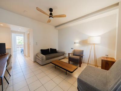 Helles Wohnzimmer mit Sofa, Sessel, Holztisch und Stehlampe in einer modernen Ferienwohnung.