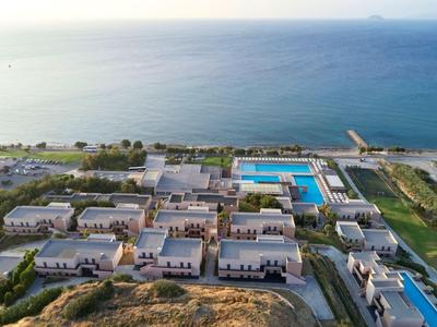 Veduta aerea di un resort con più edifici e una grande piscina vicino al mare.