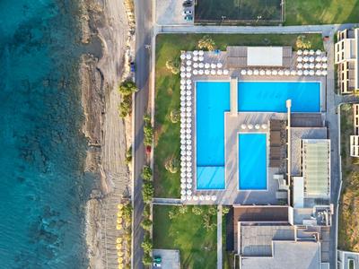 Vista aerea di un hotel con grandi piscine accanto a una spiaggia e al mare.