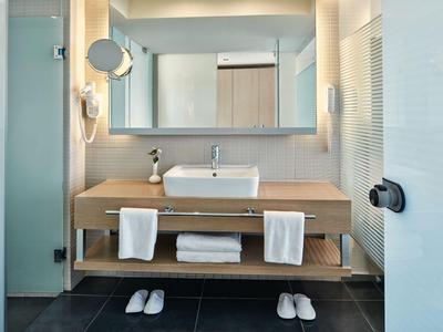 Bagno moderno con grande specchio, lavabo, asciugamani e ciabatte.